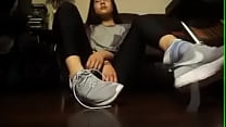 Азиатская девушка снимает теннисные туфли и носки