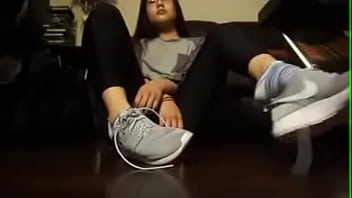 Fille asiatique enlève ses chaussures de tennis et ses chaussettes