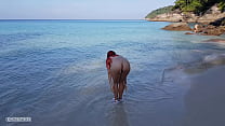 Garota ruiva nua toma banho em uma praia pública